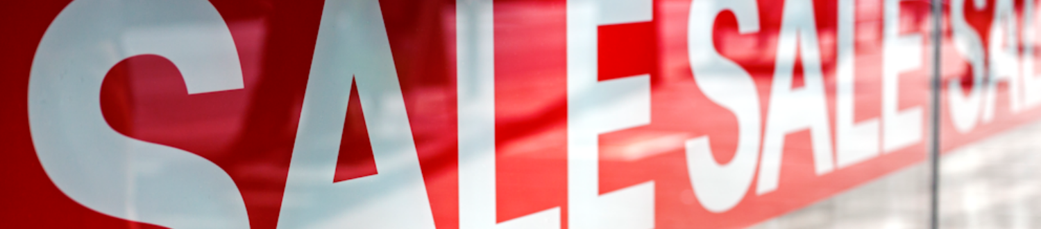 Sale items that are reduced to give you a great bargain. Piggy bank in shades, at the beach with blue sky for summer time.